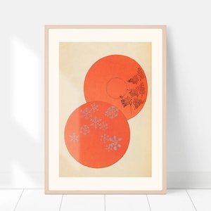 May include: Two orange circular plates with a white background. The top plate has a black fern design and the bottom plate has a silver snowflake design.