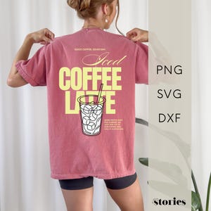 Könnte beinhalten: Ein altrosa T-Shirt mit einem Grafikdruck auf der Rückseite, der den Text "GOOD COFFEE. GOOD DAY." und "Iced COFFEE LATTE" in großen gelben Buchstaben zeigt. Darunter befindet sich eine Strichzeichnung eines Bechers mit Eis und Strohhalm.