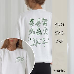 Könnte beinhalten: Weißes Sweatshirt mit grünen weihnachtlichen Grafiken auf der Rückseite, darunter Mistelzweige, eine Zuckerstange, ein Cocktail, eine Tasse heiße Schokolade, ein Weihnachtsbaum und ein Lebkuchenmann. Der Text "It's giving christmas vibes" ist ebenfalls aufgedruckt.