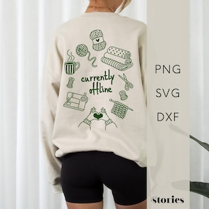 May include: A beige long-sleeve sweatshirt featuring dark green line art on the back. The design includes a sewing machine, yarn, scissors, and fabric stacks with the text "currently offline" in the centre, surrounded by hands forming a heart.