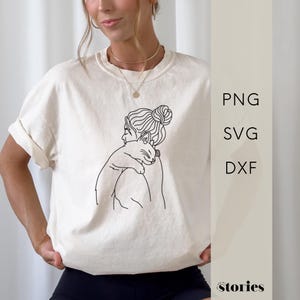 Könnte beinhalten: Cremefarbenes T-Shirt mit einer schwarzen Strichzeichnung einer Person mit Dutt, die eine Katze umarmt. Das T-Shirt hat hochgekrempelte Ärmel. Auf der rechten Seite des Bildes steht der Text "PNG", "SVG" und "DXF".