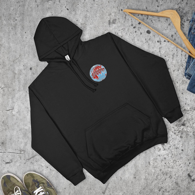 May include: Black hooded sweatshirt with a front pocket and a drawstring hood. The sweatshirt features a small embroidered globe design with red and blue accents on the upper left chest. The sweatshirt is displayed on a light grey surface.