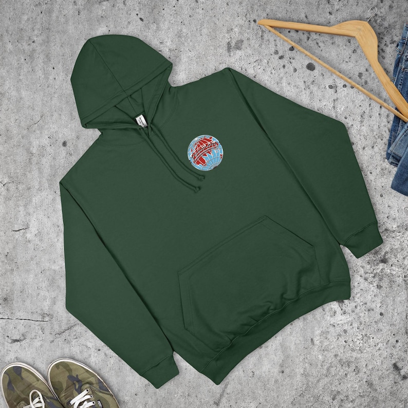 May include: A dark green hoodie with a front pocket and a drawstring hood. The sweatshirt features a circular embroidered design of a globe with red and blue accents on the upper left chest. The sweatshirt is made of a soft material.