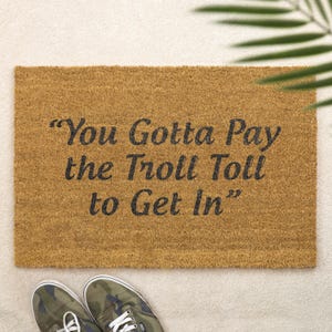 May include: A brown coir doormat with the text "You Gotta Pay the Troll Toll to Get In" in black lettering.