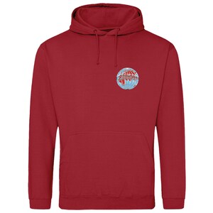 May include: A red hoodie with a front pocket and a drawstring. The sweatshirt has a circular emblem on the chest, featuring a globe design in red, white, and blue. The hoodie is made of a soft material.