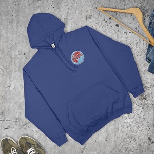 May include: A navy blue hoodie with a front pocket and a drawstring hood. The sweatshirt features a small embroidered globe design with red and blue accents on the upper left chest. The garment is made of a soft material.