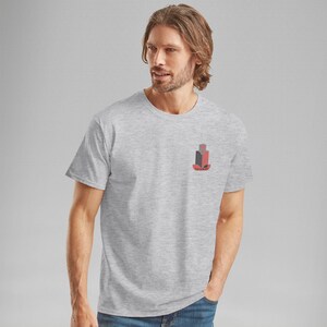 K&ouml;nnte beinhalten: Ein hellgraues T-Shirt mit einer kleinen Grafik von stilisierten Geb&auml;uden in Rot, Schwarz und Grau. Das Wort "PAIMER" ist unter den Geb&auml;uden aufgedruckt. Das Shirt ist kurz&auml;rmlig und hat einen Rundhalsausschnitt.
