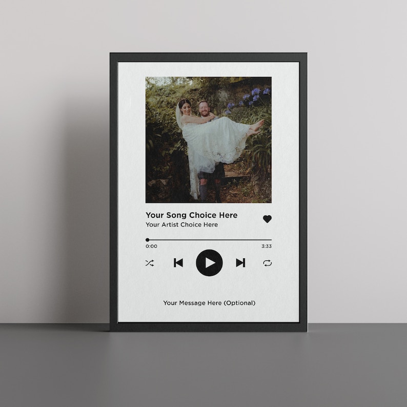 May include: A black and white photo of a couple in a garden setting. The man is holding the woman in his arms. The photo is displayed in a digital music player frame with the text "Your Song Choice Here" and "Your Artist Choice Here".