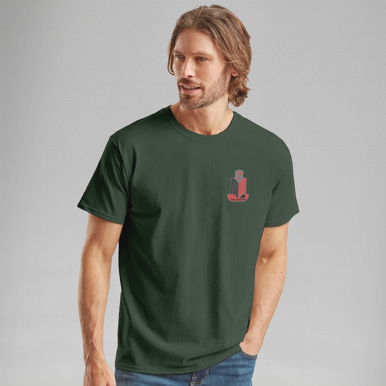 K&ouml;nnte beinhalten: Dunkelgr&uuml;nes T-Shirt mit einer kleinen Grafik auf der linken Brust. Die Grafik ist ein stilisiertes Design in Rot und Grau, das eine geb&auml;ude&auml;hnliche Form und Text darunter zeigt. Das Shirt hat kurze &Auml;rmel und einen Rundhalsausschnitt.