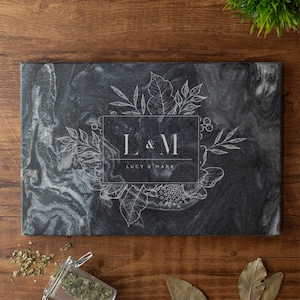May include: Black marble cutting board with a white floral design and the initials "L & M" with the text "Lucy & Mark" below.