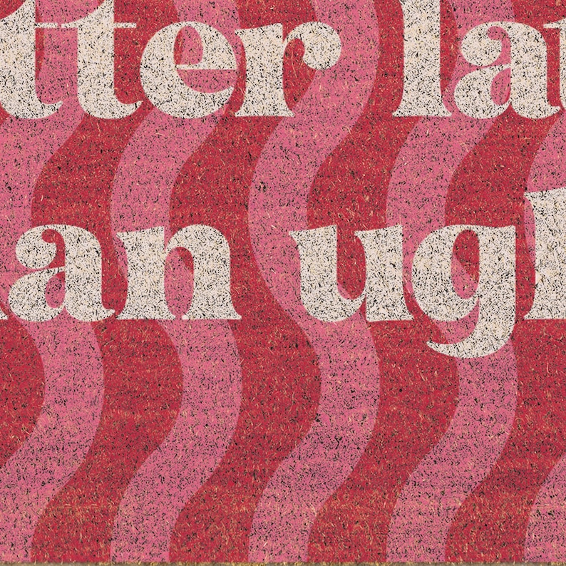 May include: A doormat with a wavy pattern in shades of red and pink. The text "better late than ugly" is displayed in a white, retro font. The mat is made of a textured material.