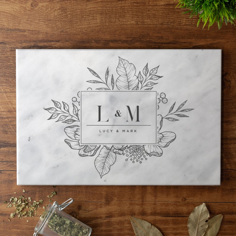 May include: White marble cutting board with a floral design and the initials "L & M" in a rectangle with the text "Lucy & Mark" below.