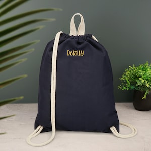 May include: A navy blue drawstring bag with white drawstrings and the word "Dorelly" embroidered in gold on the front.
