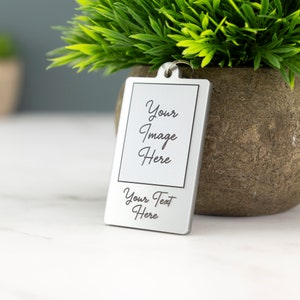 May include: Silver keychain with a rectangular photo frame and space for a personalized image and text. The text reads "Your Image Here" and "Your Text Here".