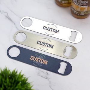 May include: Three silver bottle openers with a custom design. The design features a sunburst with the word "CUSTOM" in the center. The text "YOUR DESIGN HERE" and "YOUR LOGO HERE" are also included in the design.