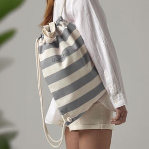 May include: A grey and white striped drawstring bag with the name "Charlotte" embroidered on the front.