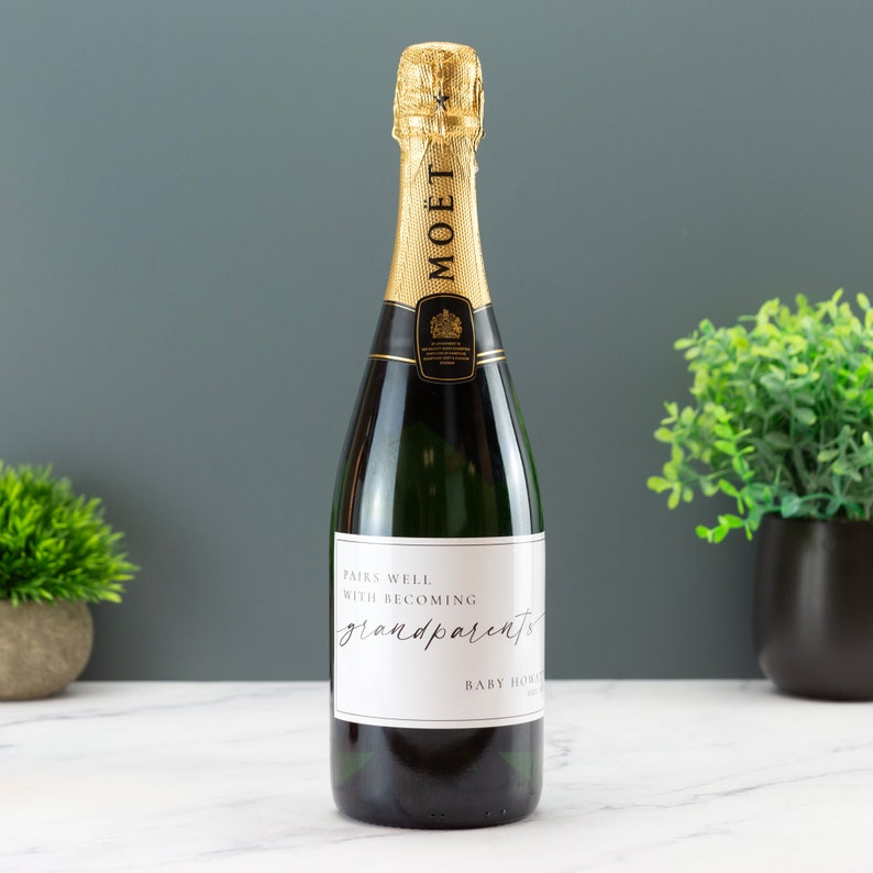 May include: A bottle of champagne with a white label that says "Pairs well with becoming grandparents".