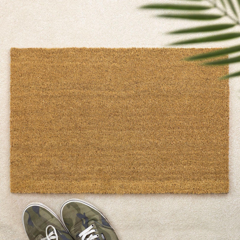 May include: A brown coir doormat with a textured surface. The doormat is on a white surface.
