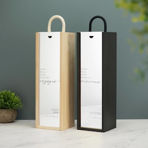 May include: Two wooden wine bottle gift boxes with white labels. The left box has a white label with the text "Pairs well with getting engaged" and the text "Mick & Pam 4th October 2021". The right box has a white label with the text "Pairs well with being a bridesmaid" and the text "Steph 8 July 2021".
