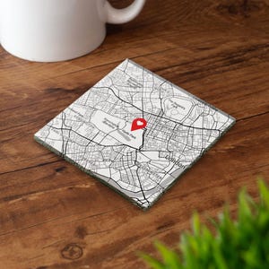 May include: A square coaster featuring a black and white map of London, England. The design displays street layouts and park names, with a prominent red heart-shaped location pin marker placed over the Hyde Park and Kensington Gardens area.
