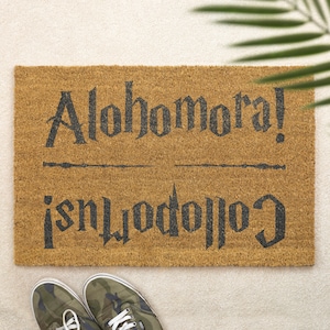 May include: A brown doormat with the text "Alohomora!" and "Colliwobbles" in black lettering. The text is in a stylized font.