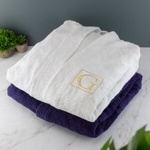 May include: White bathrobe with a navy blue trim and a gold embroidered letter G on the front.
