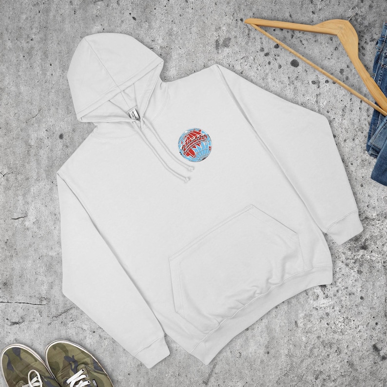 May include: White hooded sweatshirt with a front pocket and a drawstring hood. The sweatshirt features a colorful embroidered globe design on the upper left chest. The design includes red, blue, and white colours. The sweatshirt is made of a soft material.