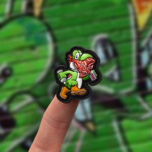 May include: A green cartoon character wearing a red bandana and holding a spray can. The character is walking and has a black outline.