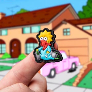 Może przedstawiać: Żółto-włosy bohater kreskówki w niebieskim kombinezonie i czerwonej bandanie z maską przeciwgazową. Postać trzyma w jednej ręce puszkę ze sprayem, a w drugiej puszkę z dyszą. Postać siedzi na czarnej podstawie.