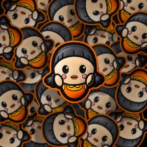 May include: A close-up of a repeating pattern of orange and black embroidered patches featuring a cartoon girl with black hair, a yellow dress, and a pink blush.