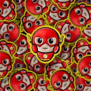 May include: A collection of red and yellow Flash character stickers. The stickers feature the Flash's face with a red mask, yellow accents, and a lightning bolt emblem. The stickers are arranged in a scattered pattern.