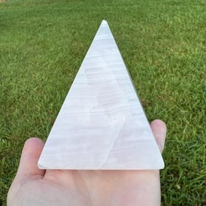 Op de afbeelding: Een witte seleniet piramidekristal. De piramide is glad en heeft een doorschijnende uitstraling.