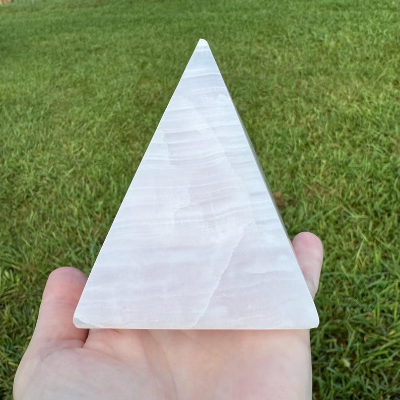 Op de afbeelding: Een witte seleniet piramidekristal. De piramide is glad en heeft een doorschijnende uitstraling.