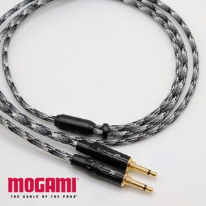 May include: A black and grey camouflage audio cable with two gold-tipped 1/4 inch plugs. The cable is labeled "Mogami" and "The Cable of the Pros".