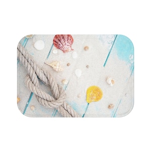 May include: A blue and white wooden surface with sand and seashells. A rope is tied in a knot on the surface. The seashells are in various colors, including white, yellow, pink, and brown.