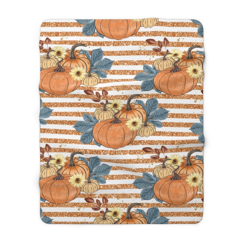 May include: A white and gold striped background with a repeating pattern of orange pumpkins, blue leaves, and yellow flowers. The pumpkins are arranged in groups of three, with the largest pumpkin in the center.
