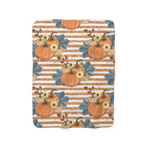May include: A white and gold striped fabric with a repeating pattern of orange pumpkins, yellow flowers, and blue leaves.
