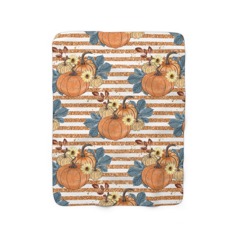 May include: A white and gold striped fabric with a repeating pattern of orange pumpkins, yellow flowers, and blue leaves.
