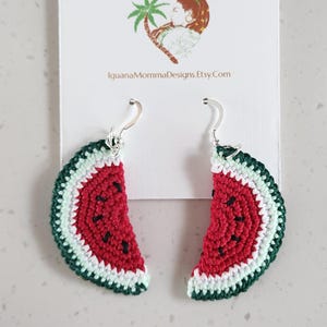 May include: Crocheted watermelon slice earrings with silver hooks. The earrings are red, green, and white.