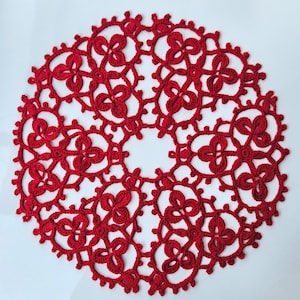 May include: A red crocheted doily with a delicate floral pattern. The doily is circular and has a lace-like design.