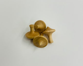 May include: Four wooden spinning tops in various sizes and shapes. The tops are made of light brown wood and have a smooth, polished finish.