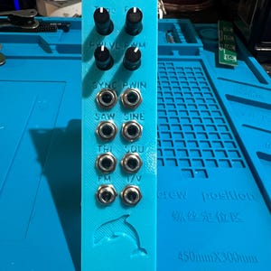 Puede incluir: Módulo electrónico turquesa con la inscripción "Dolphin VCO", perillas negras y conectores de entrada. El módulo tiene etiquetas de texto que incluyen "PHVLPWM", "SYNC PWIN", "SAW SINE", "TRI SOU", "FM" y "1/V". Un gráfico de delfín en la parte inferior.
