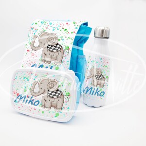 Può includere: Una borsa per il pranzo blu e bianca con un motivo a spruzzo colorato e un design a forma di elefante. La borsa è abbinata a una scatola per il pranzo e a una borraccia in tinta, tutte con il nome "Miko".