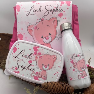 Può includere: Zaino rosa con un designo di gatto rosa e il nome "Liah Sophie" stampato su di esso. Sono inclusi anche una lunchbox rosa abbinata e una borraccia con lo stesso design e nome.