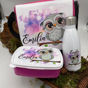 Può includere: Borsa da pranzo rosa con un design di gufo bianco e il nome "Emilia" stampato su di essa. Sono inclusi anche una lunchbox rosa abbinata e una borraccia in acciaio inossidabile con lo stesso design di gufo e nome.