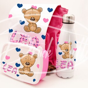 Può includere: Un set di zaino, lunchbox e borraccia rosa e bianca con un orso dei cartoni animati e il nome "LEA" stampato su ogni articolo. Il set presenta un motivo a pois rosa e bianco.