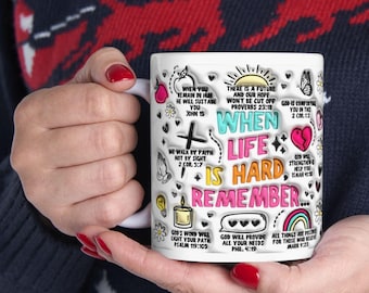 May include: White ceramic mug with a colorful design featuring bible verses and the phrase "When life is hard, remember..." The mug is decorated with hearts, flowers, and other illustrations.