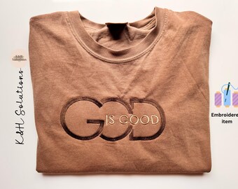 May include: A brown t-shirt with the words "God is Good" embroidered in gold on the front.