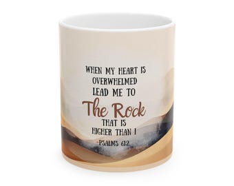 May include: White ceramic mug with a beige and brown landscape design. The mug features the text "WHEN MY HEART IS OVERWHELMED LEAD ME TO The Rock THAT IS HIGHER THAN I -PSALMS 61:2" in black and brown lettering.