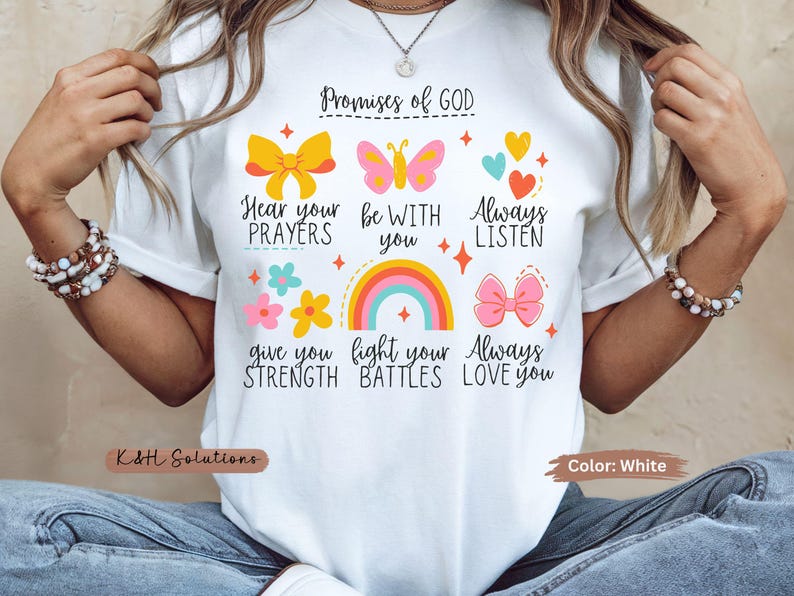 May include: White t-shirt with colorful graphics and text. The design includes a rainbow, butterflies, bows, hearts, and flowers, along with the words "Promises of GOD". The shirt is a casual wear item.